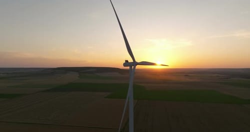 Alternative Energy Large Wind Turbines with Blades in Field Aerial View Bright Orange Sunset Blue
