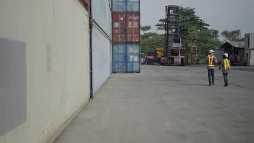Blue collar workers are working at container warehouse.