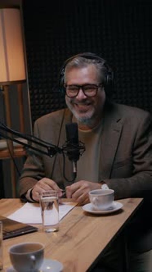 Mature Caucasian Podcast Journalist Listening to Guest and Laughing