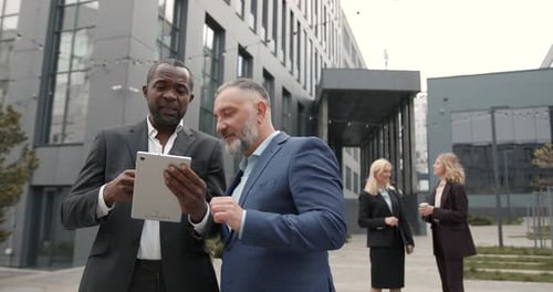 Business Men Reviewing Data on Tablet Outdoors