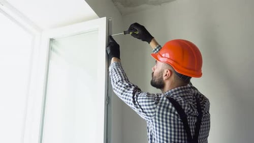 A Repairman in Uniform and Helmet Fixing Pvc Windows in New Apartment