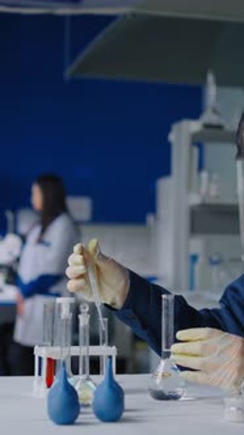 Scientist Works With Beakers and Dropper in Lab