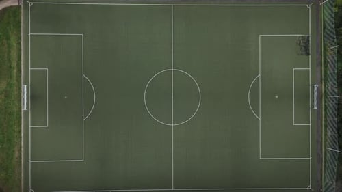 Top Down View of an empty, green football field in the middle of the forest, Drone Footage