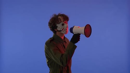 Man in White Mask with Loudspeaker in Hands on Blue Background with Red Neon Light Image of Maniac
