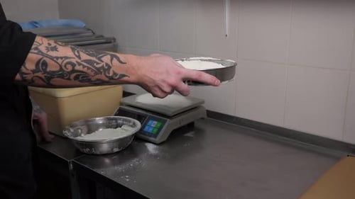 The Chef of the Restaurant Sifts Flour on the Dough Table