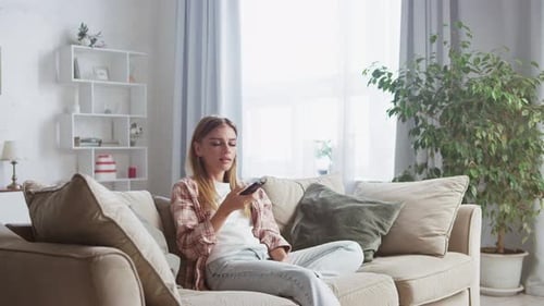 Woman Relaxes at Home, Using TV Remote