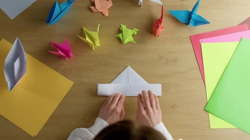 Overhead Shot of Hands Folding Origami on Table