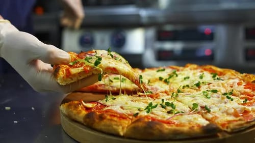 Hand Takes Fresh Slice of Gourmet Pizza