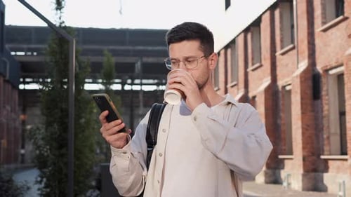 Male Typing Message Chatting on Cellphone Standing on Urban Street Outside