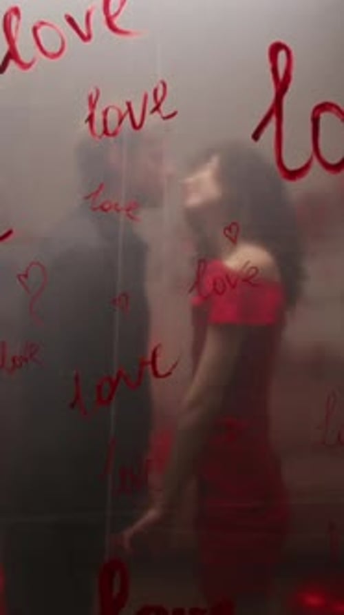 Young Couple Kissing Behind Love-Themed Glass