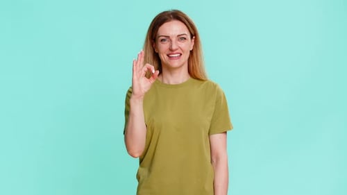 Smiling Woman Giving Okay Sign on Light Blue Background