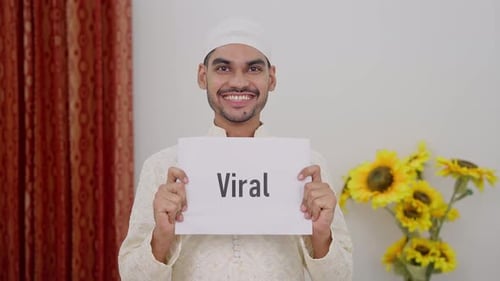 Young Adult Smiling and Holding Viral Sign