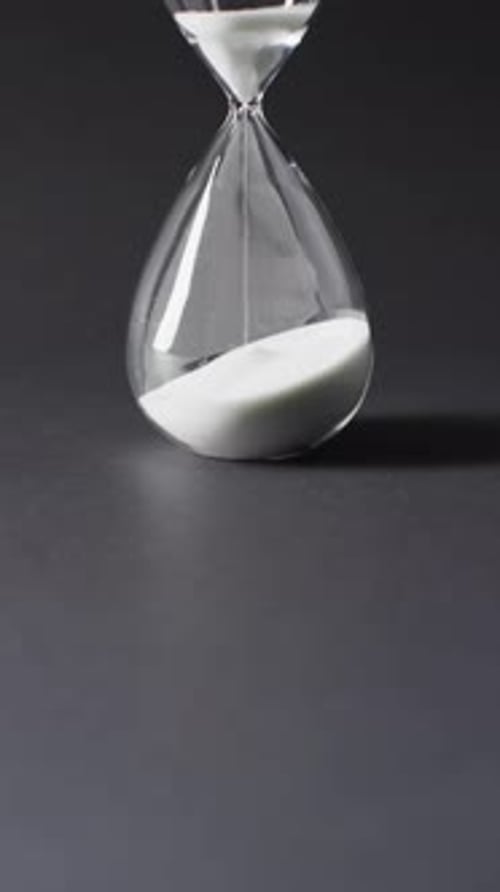 Vertical video of hourglass with sand pouring, copy space on black background