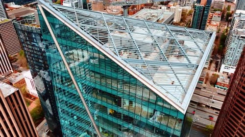 Futuristic skyscraper of glass and concrete. Drone distancing from the top of the building at day.