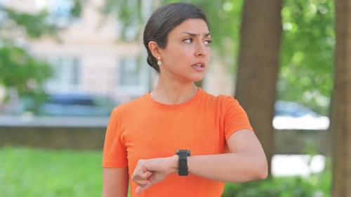 Woman Checks Smartwatch in Park on Bright Day