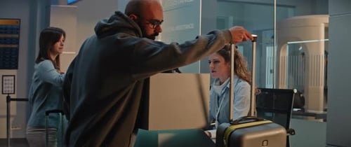 Female Airline Worker Checks in Luggage at Counter Puts Baggage Tag Sticker on Suitcase