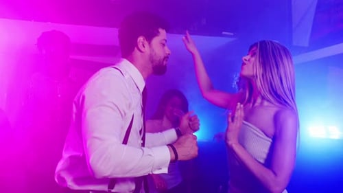 Energetic Young Adults Dancing in Neon Nightclub