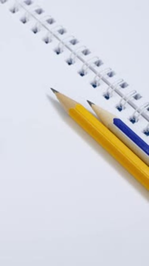 Blank Paper Notepad with Yellow and Blue Binder Clips on Blue Background