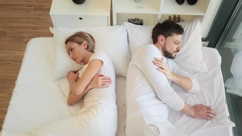 Offended Caucasian Woman Lying on White Pillow Covered with a Blanket
