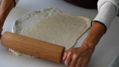 Woman Rolling Dough with Rolling Pin on Table