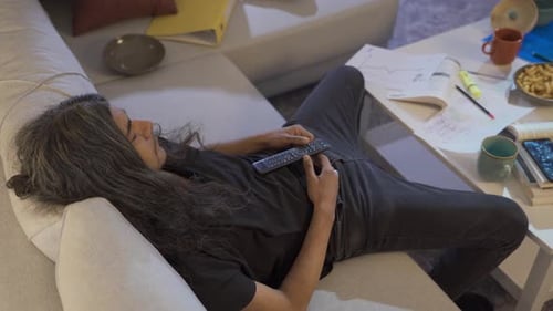 Messy and lazy man falls asleep while watching tv.