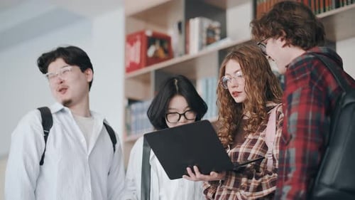 Diverse students working together on laptop at university library