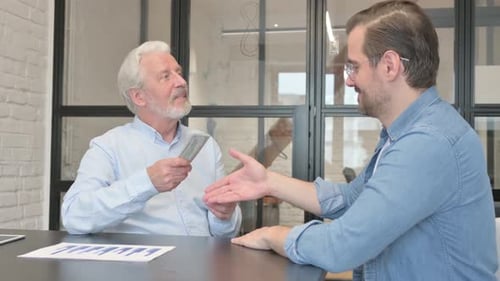 Young Man Gives Money and Shakes Hand with Old Man