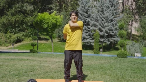 Man Stretching Upper Body on Yoga Mat in Park