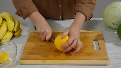 Person Peeling a Fresh Orange in Kitchen