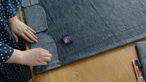 Tailor Hands Adjusting Fabric for Sewing on a Table