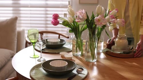 Woman Sets Table with Flowers for Meal at Home