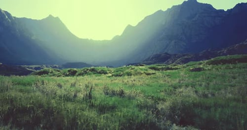 Majestic Mountains with Lush Green Fields at Sunset in a Serene Valley