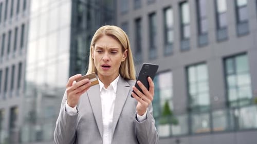 Frustrated businesswoman discovered fraud while checking credit card on phone standing on street