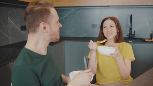 Cheerful Couple Eating Breakfast and Chatting in Kitchen