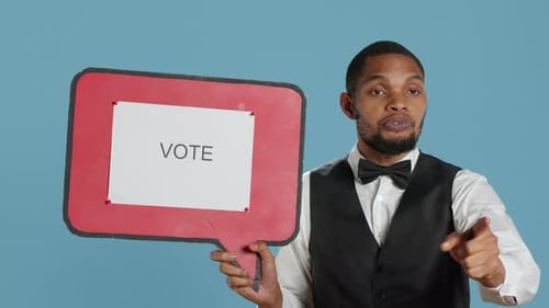 Young Adult Holding a Vote Sign Points to Camera