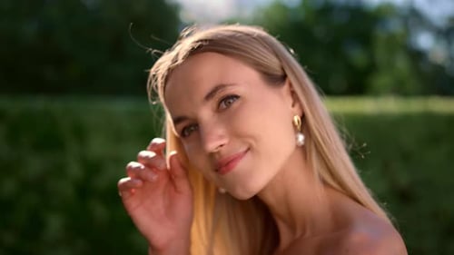 Elegant woman with blonde hair smiles in park