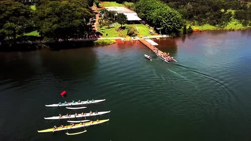 Aerial view above lakeside jetty rowing teams preparing for lake water sport practice racing