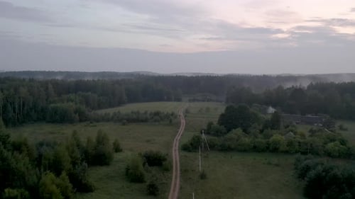 Drone flight over a country road during a foggy sunset