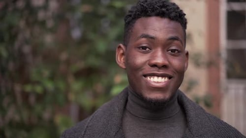 Young black man close-up face smiling, looking at camera portrait