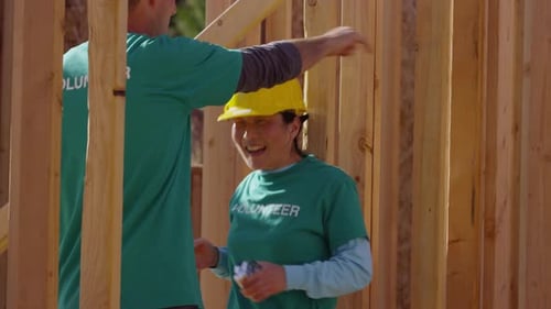Volunteers measure wood on construction site teamwork