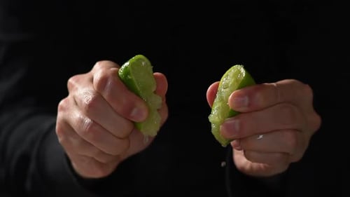 CU SLOW MOTION: Cook holds chopped lime and squeezes fresh juices out of it