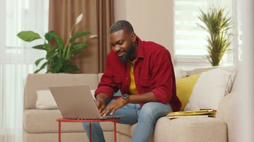 Man Working on Laptop at Home on Sofa
