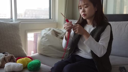 Eine Frau strickt beim Anschauen eines Video