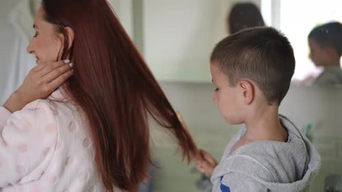 Little Boy Brushing Woman's Long Auburn Hair