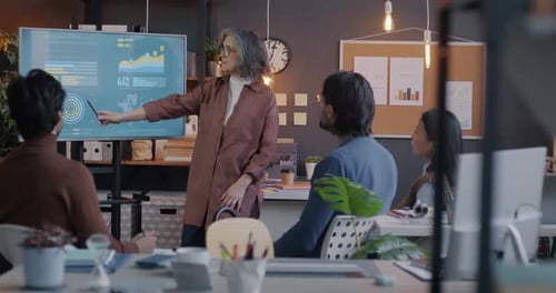 Slow Motion of Senior Business Lady Speaking to Diverse Group of Colleagues Pointing at Digital