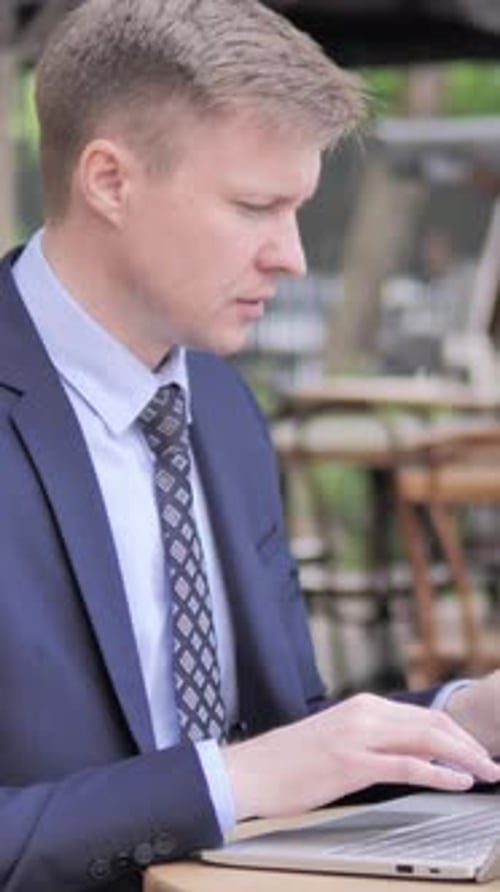 Businessman Working on Laptop and Drinking Coffee in Outdoor Cafe, Vertical Video