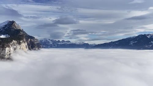sheer swiss cliffs overlook a vast cloud ocean framed by distant snowy alpine peaks