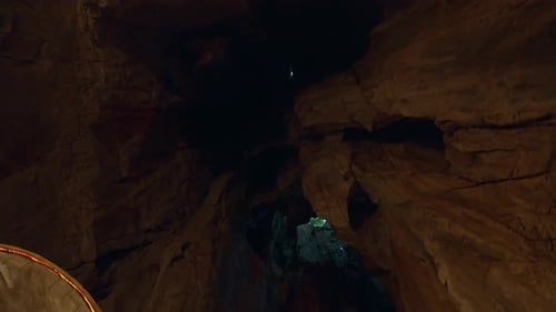 Helle natürliche Öffnung an der Spitze der dunklen Höhle beleuchtet raue Felswände und schafft so einen Kontrast zwischen