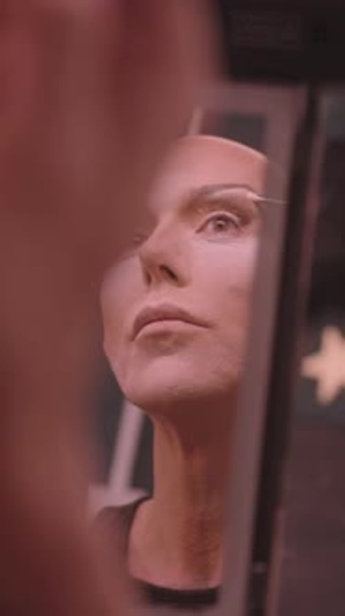 Man Applying Makeup to Face in Mirror