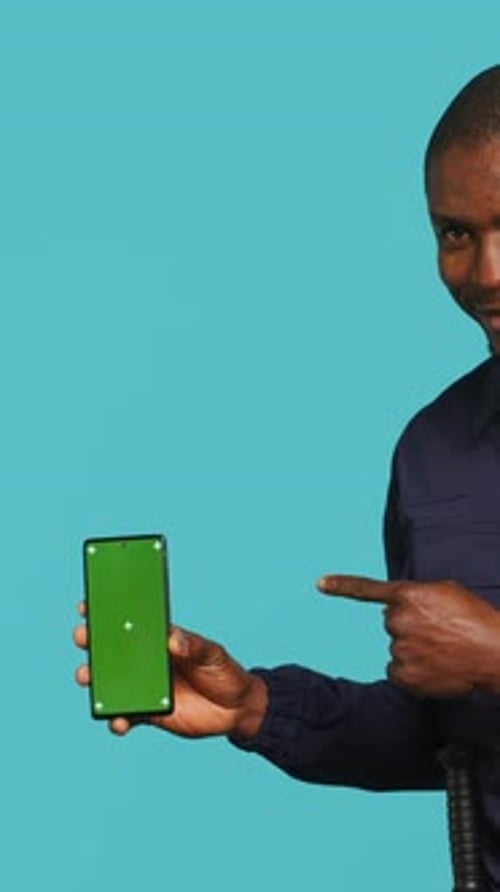 Vertical Video Portrait of Upbeat Bodyguard Showcasing Green Screen Phone